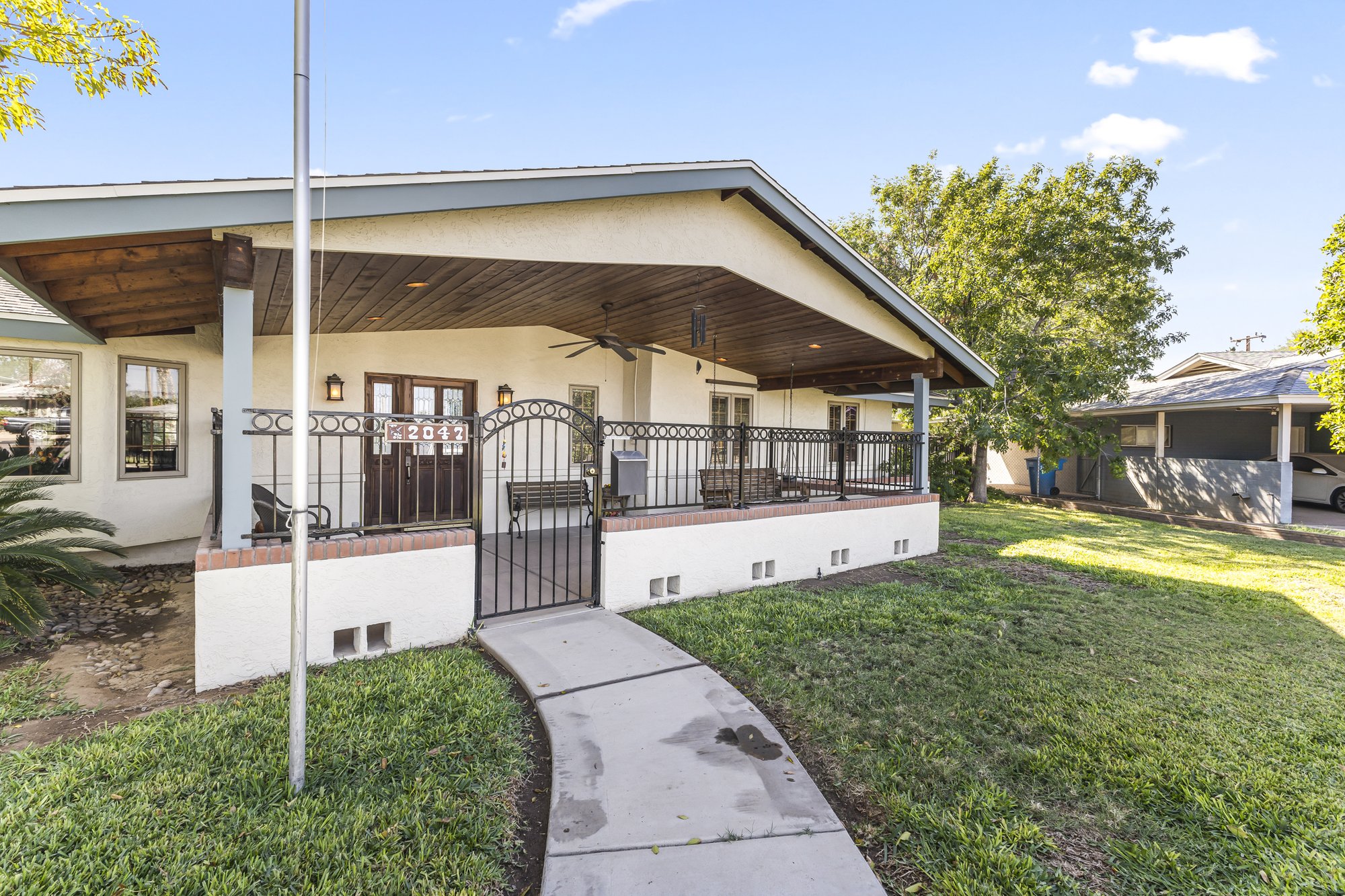 Front exterior of 2047 W Cambridge Ave in Phoenix with a covered porch and mature landscaping