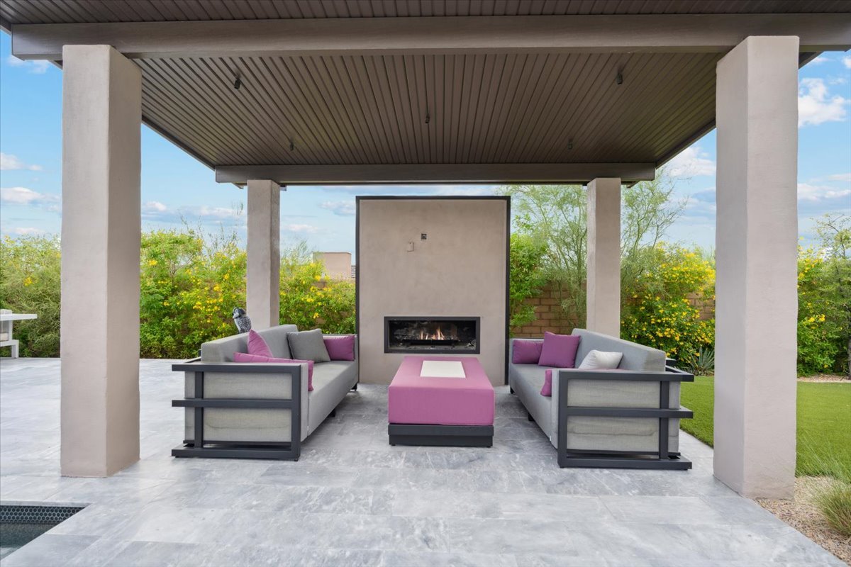 Covered patio lounge area with an outdoor fireplace