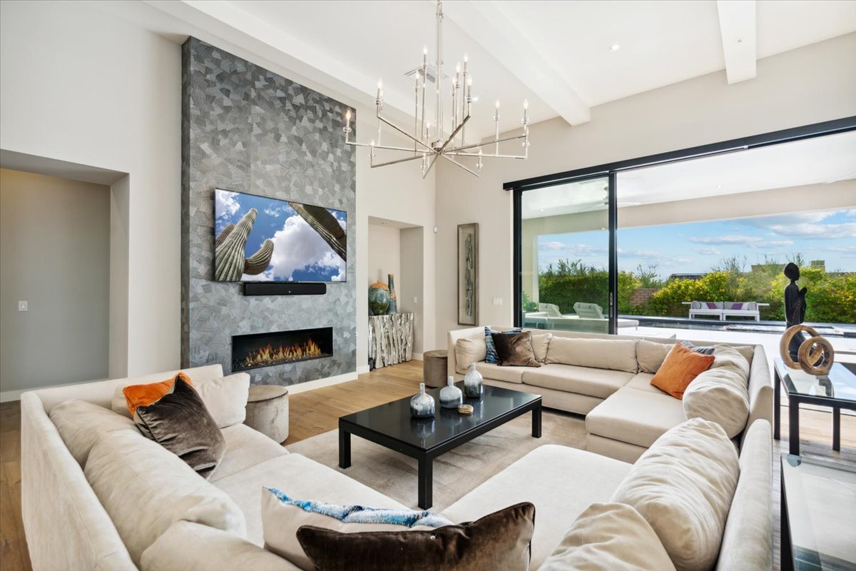 Great room with a fireplace and walls of glass opening to the patio