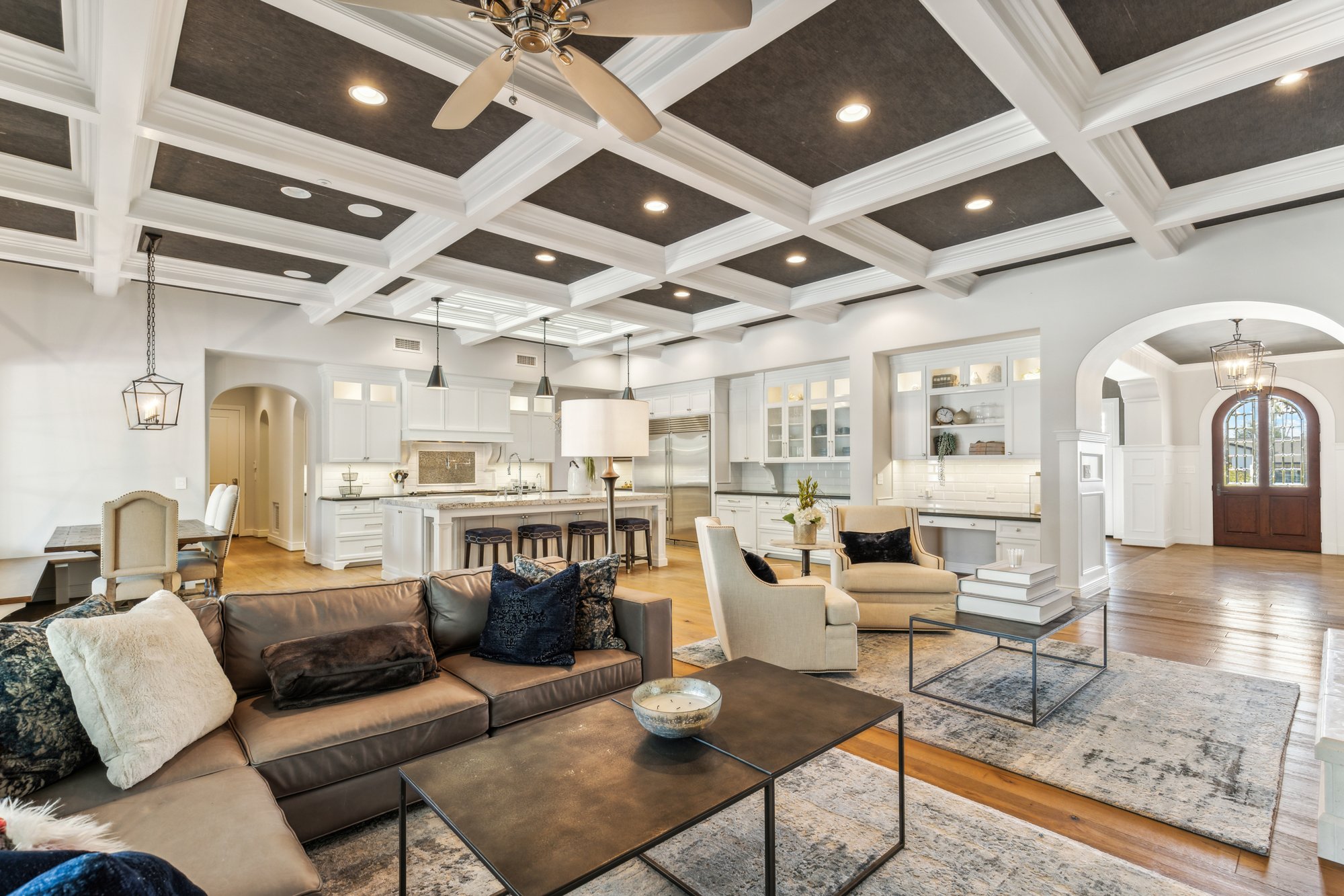 Open concept great room with coffered ceiling and skylights