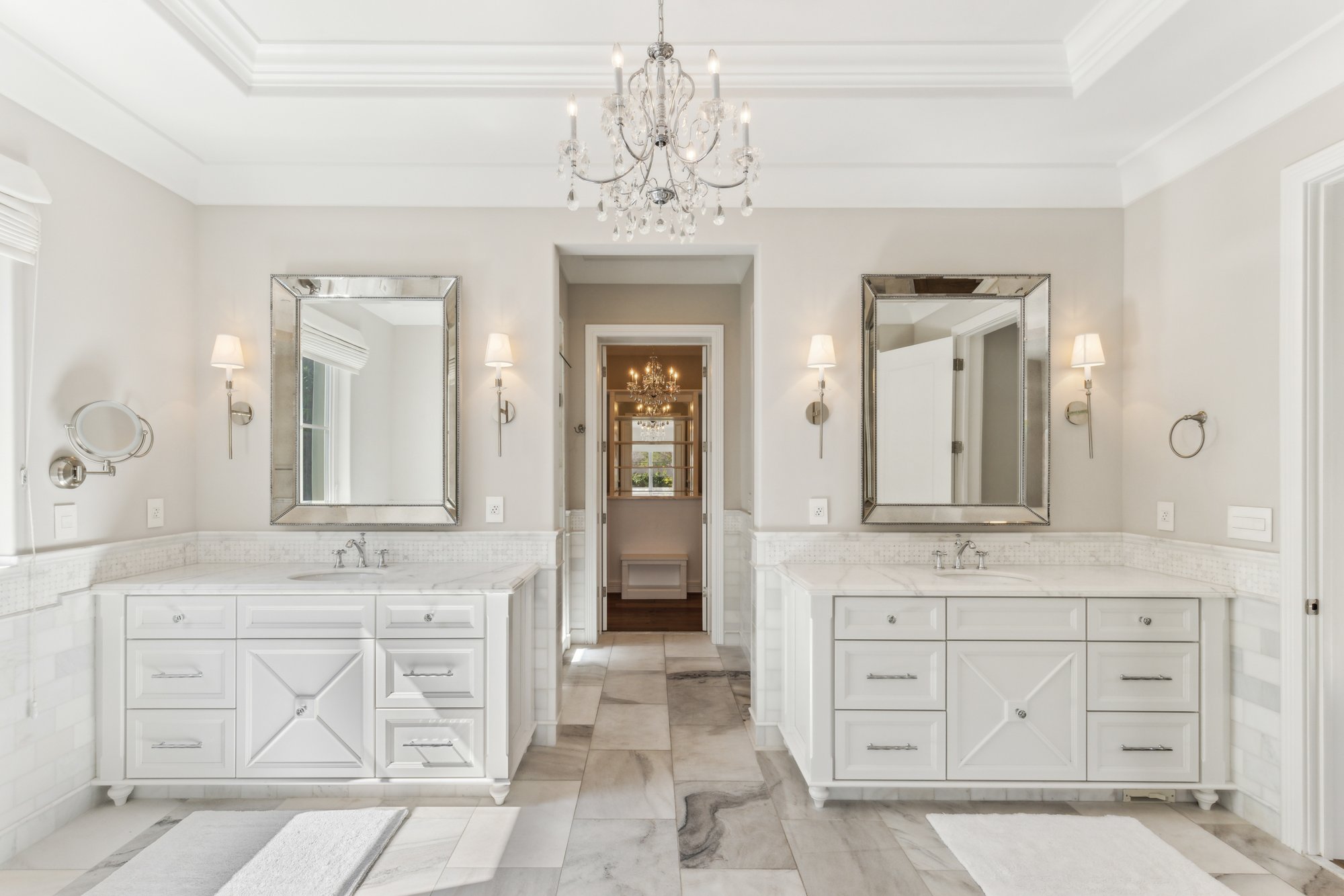 Primary bathroom with dual vanities and chandelier