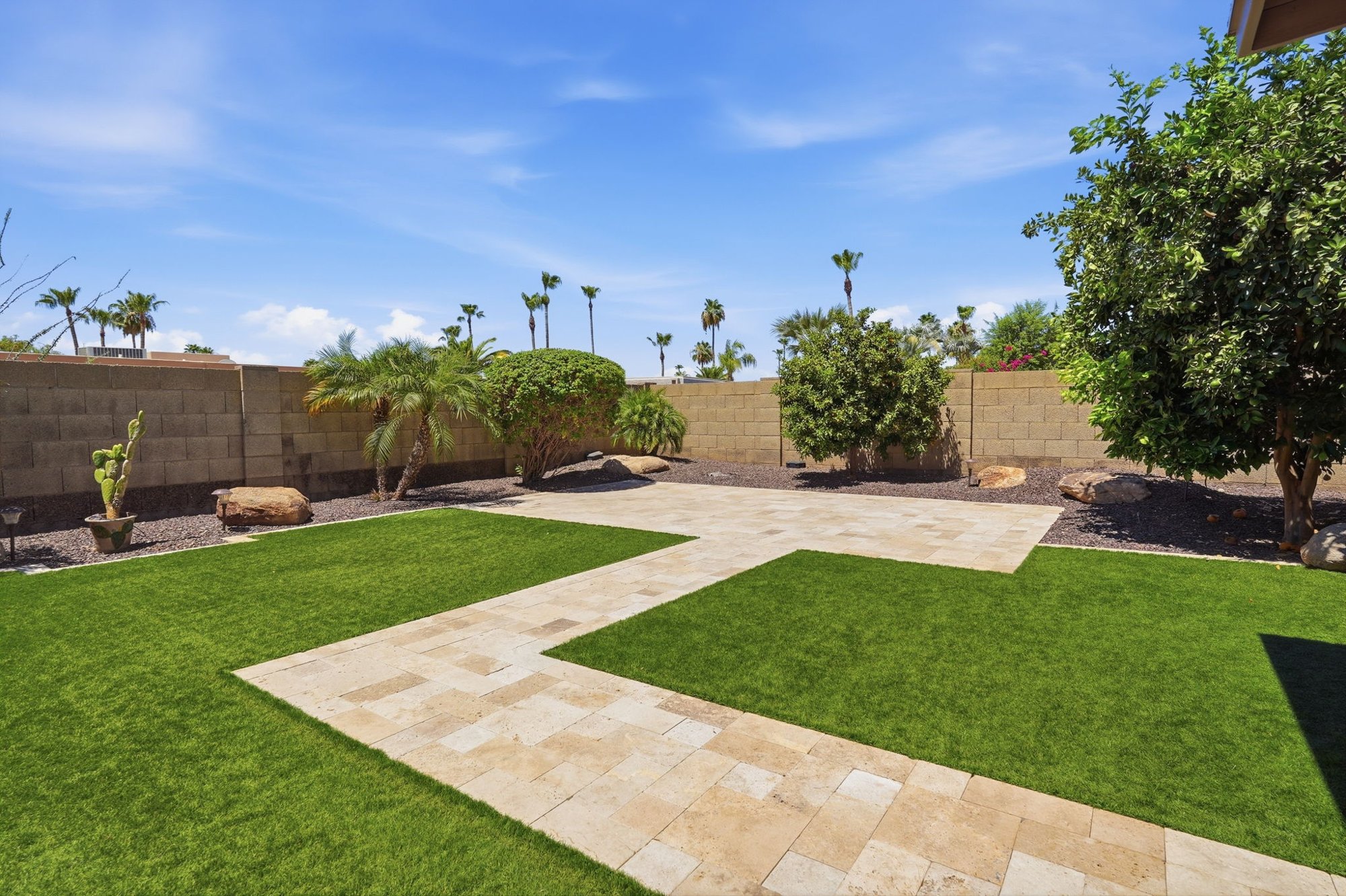 Backyard with synthetic grass and travertine pavers