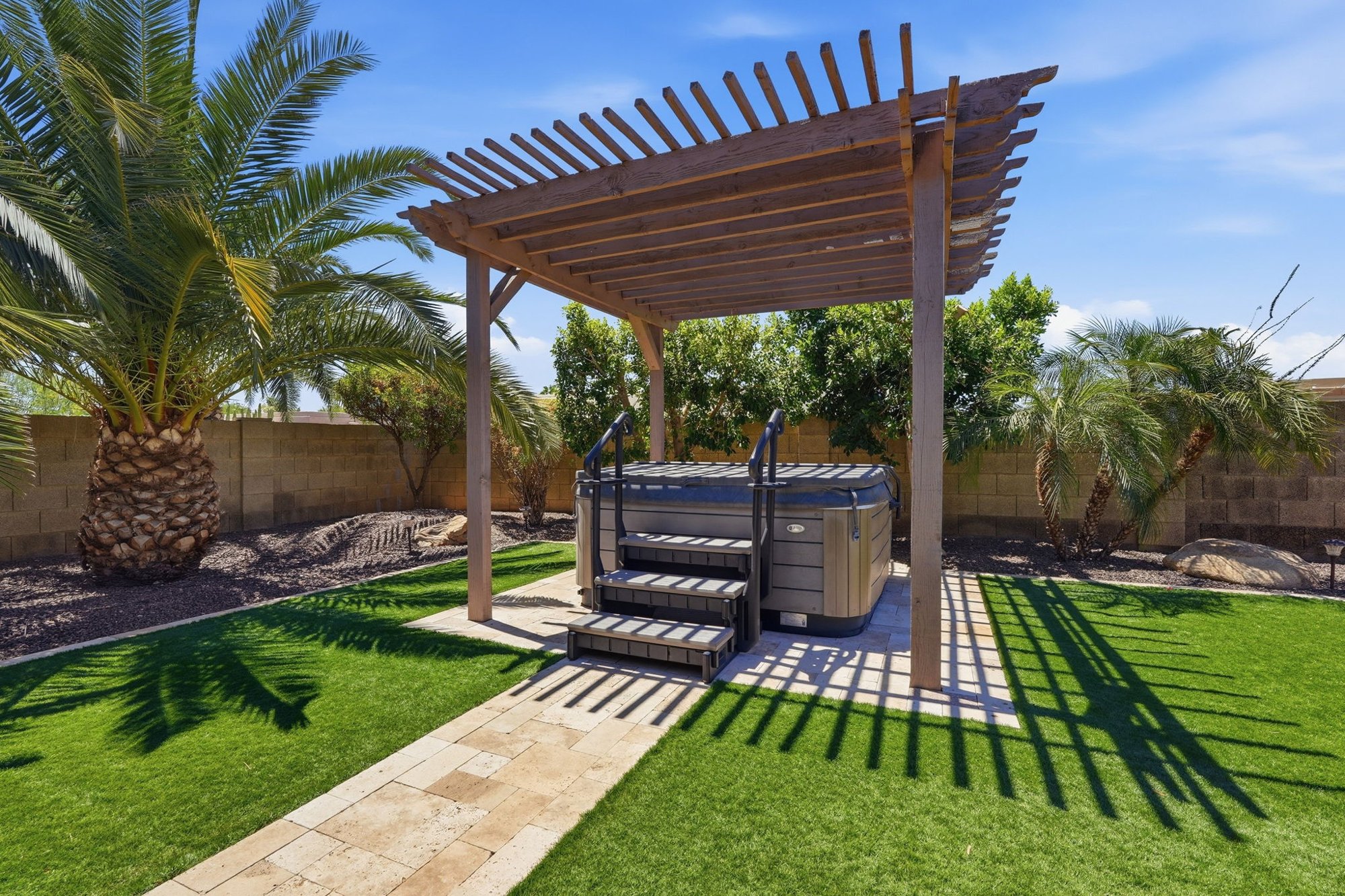 Private heated spa under a wood pergola in the backyard