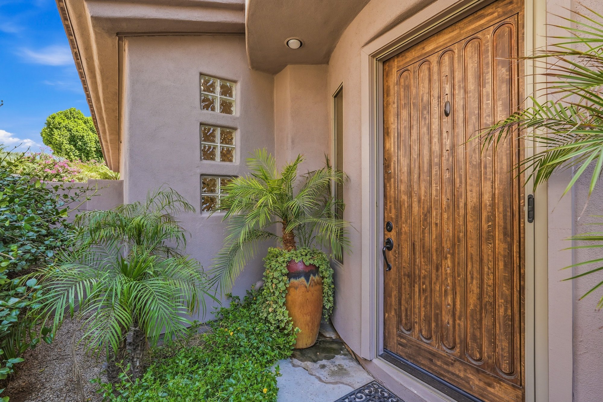 Private courtyard entry with a wood front door and desert landscaping