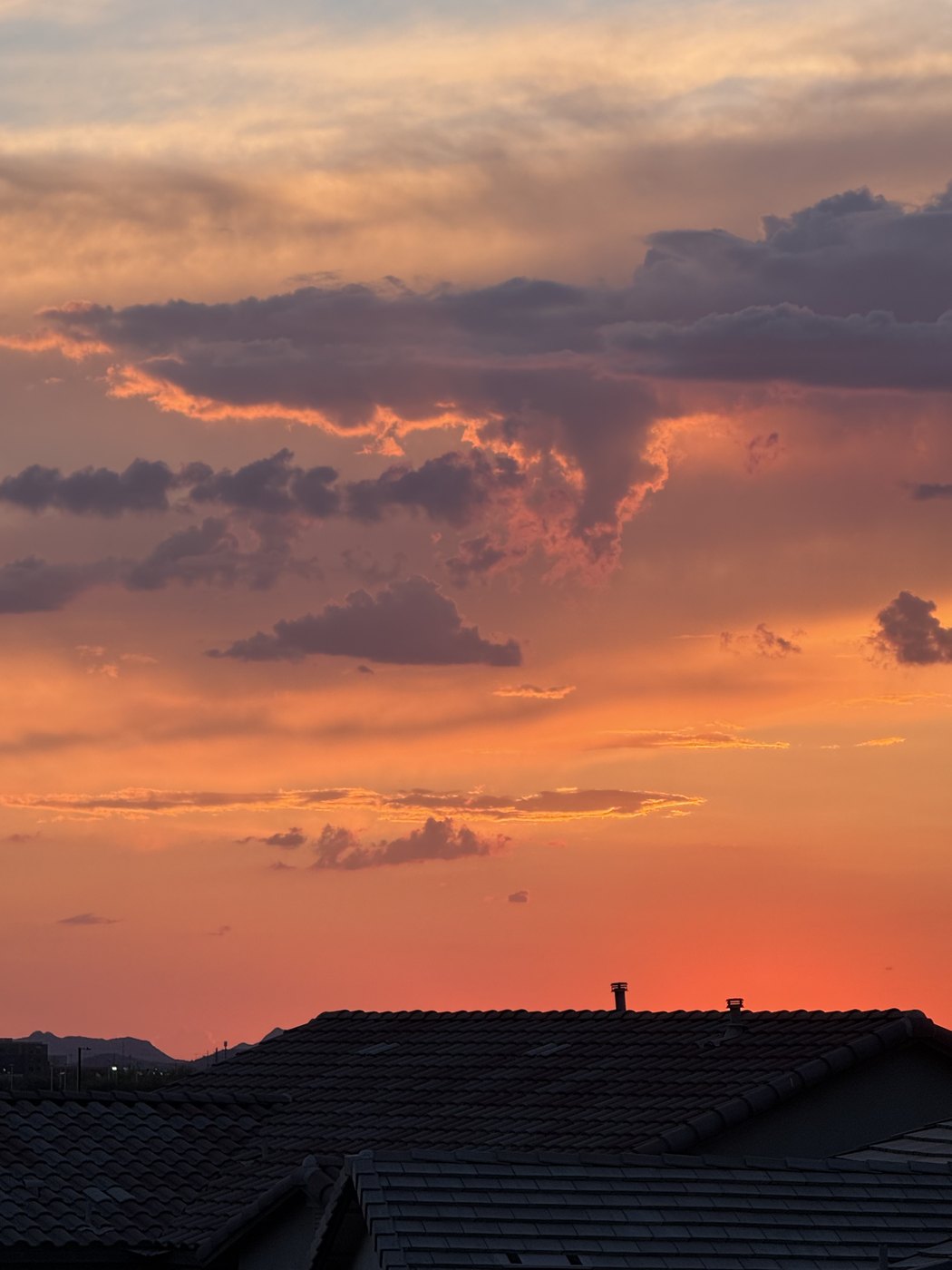 Orange and pink storm clouds at sunset over rooftops