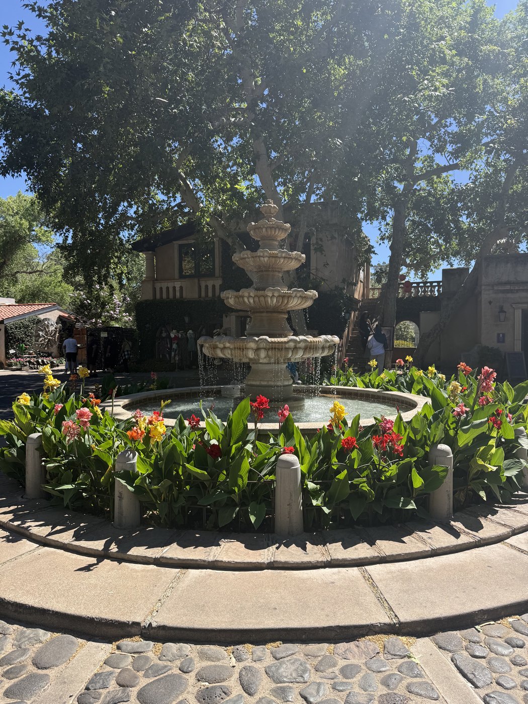 A tiered stone fountain surrounded by blooming flowers