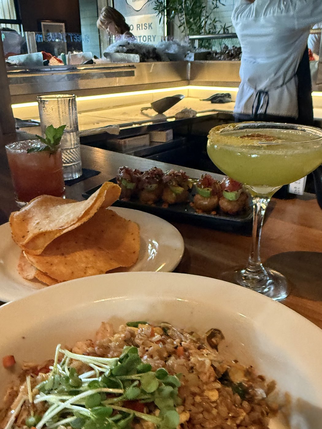 A bowl of fried rice, chips, and cocktails at a restaurant bar