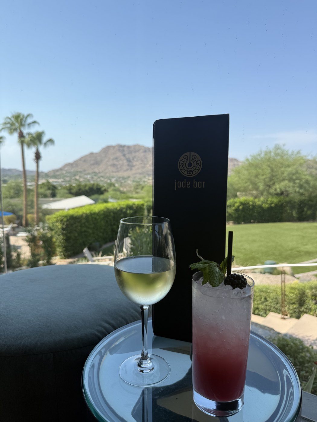 Wine and a cocktail on a table at Jade Bar with Camelback Mountain in the background